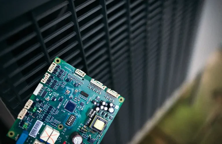 Technician holding an air-conditioner control board near an indoor unit